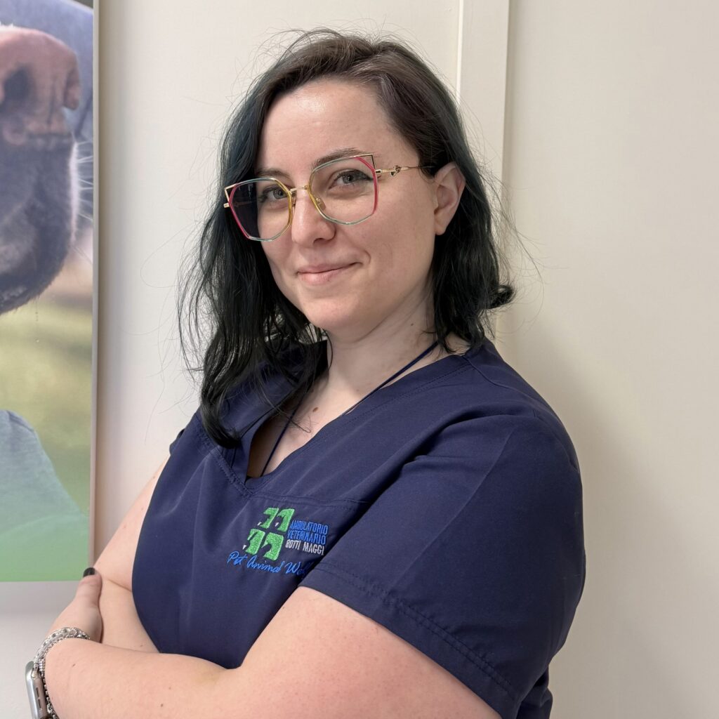30.1 Primo piano della Dott.ssa Denise Omini veterinaria dell'Ambulatorio Veterinario Botti Maggi. Una donna in camice medico sta in piedi con le braccia incrociate e guarda la telecamera. Ha capelli scuri fino alle spalle e porta gli occhiali